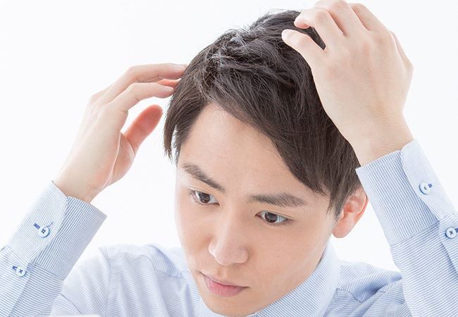 髪の毛の状態をチェックする男性